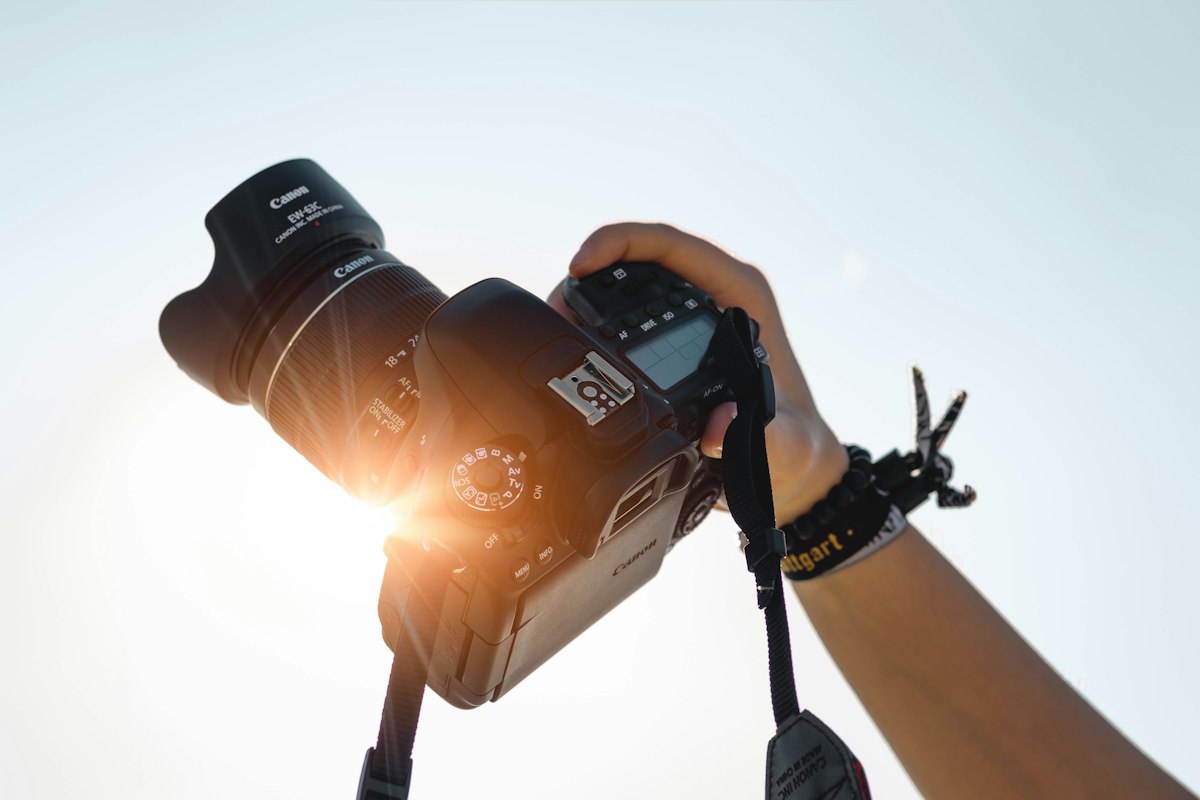 Ruka drží fotoaparát proti nízkému slunci